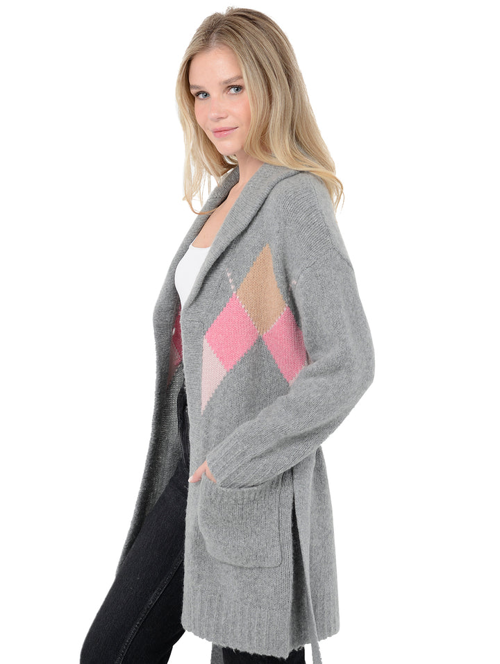 Side view of model wearing Tuscany in flannel grey. The sweater is long and oversized and made of wool, cashmere, and nylon. The sweater features a tie around the waist and patch pockets.