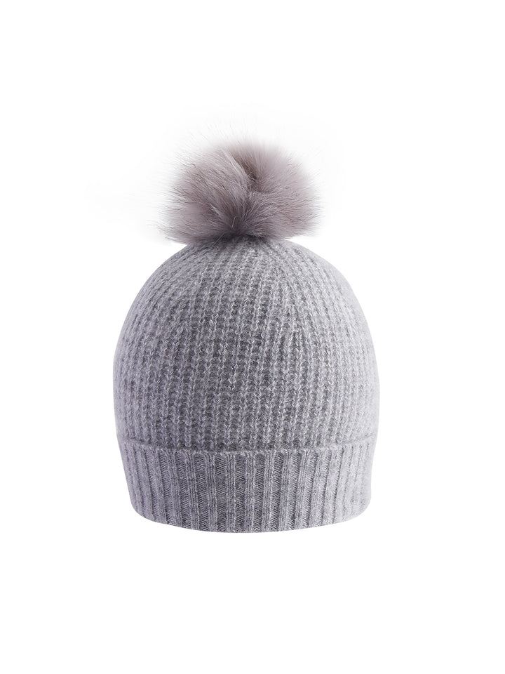 Flatlay photo of Rivka beanie in heather grey. The beanie is made of 75% cashmere and 25% filament silk. The beanie has a 3x3 rib trim at the bottom and a puffball on top.