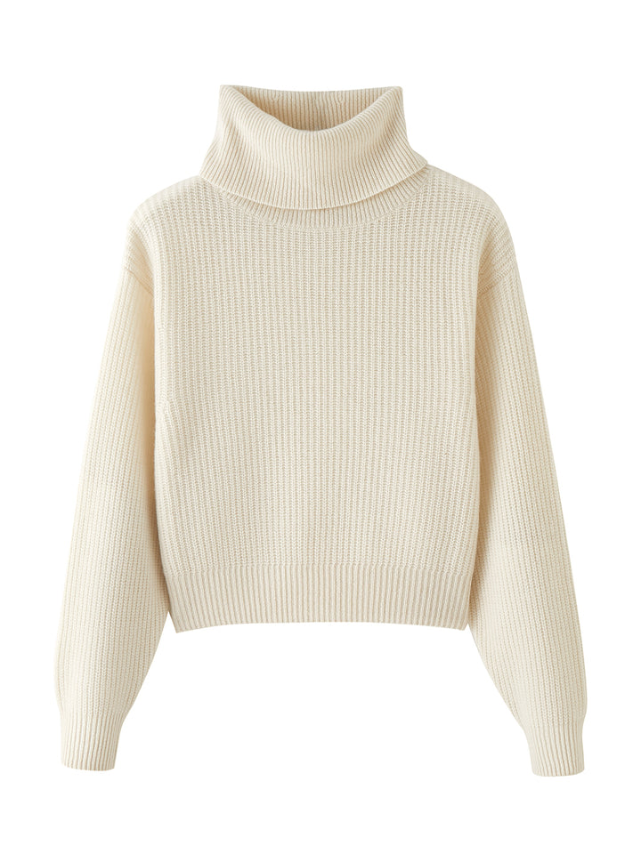 Flatlay photo of Naia in cloud white. The sweater is oversized and cropped and made of cashmere and recycled cashmere. The sweater is a ribbed knit turtleneck.