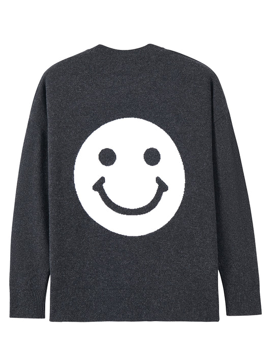Flatlay photo of Jezebel in gravel grey. The sweater is oversized and made of 100% cashmere. The crewneck pullover has a large smiley face graphic on the back.