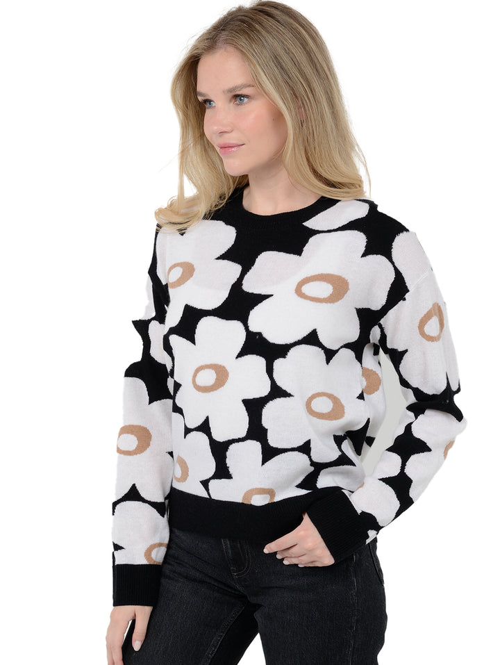 3/4 front view shot of model wearing Dulce in black and white. The sweater is relaxed and made of wool cashmere blend. The sweater sports a retro floral print with black cuffs and trims.