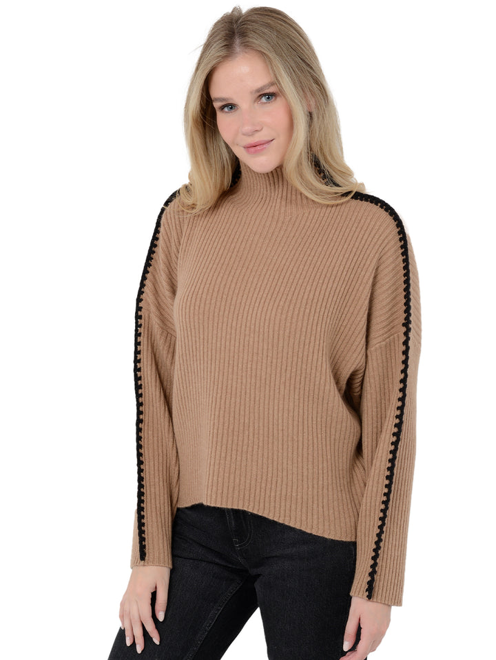 3/4 front facing shot of model wearing Marullo in camel brown. The sweater is oversized and made of wool and cashmere. The sweater is a mock neck with crochet-like embroidery along the sleeves and shoulders.
