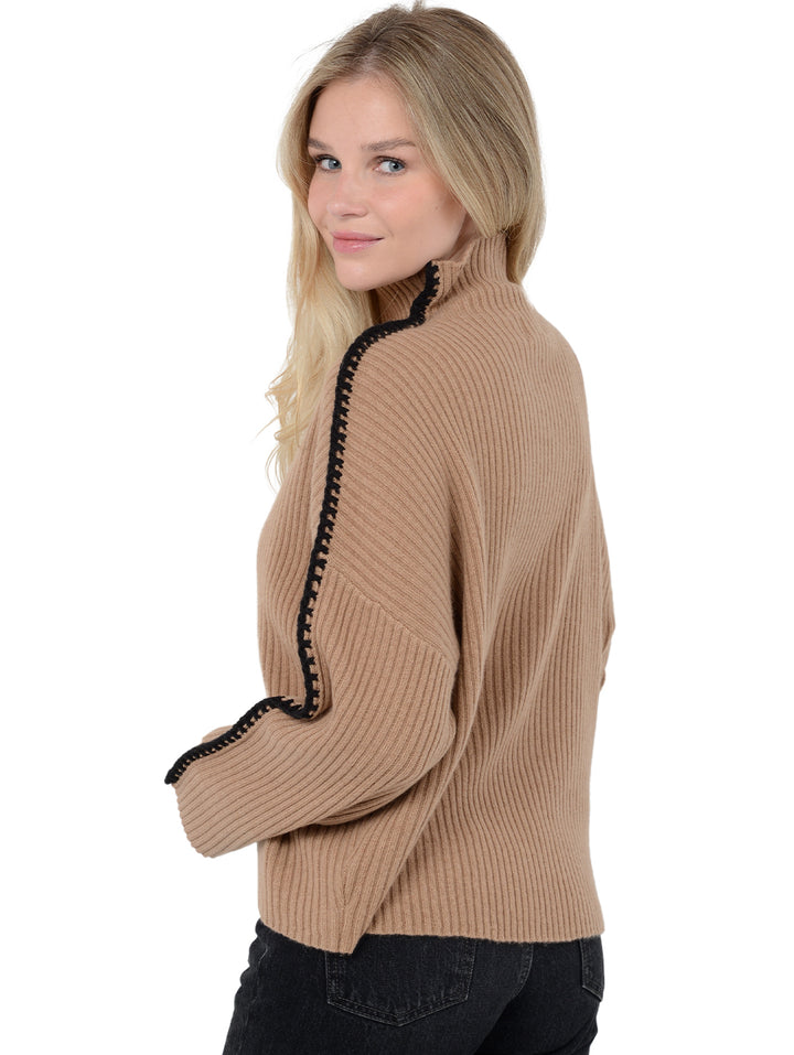 3/4 back facing shot of model wearing Marullo in camel brown. The sweater is oversized and made of wool and cashmere. The sweater is a mock neck with crochet-like embroidery along the sleeves and shoulders.