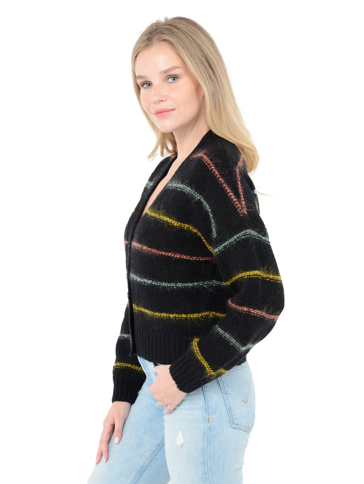 Side view of model wearing Micaela in black. The sweater is oversized and cropped and made of wool and cashmere with contrasting stripes in wool, nylon, and mohair.