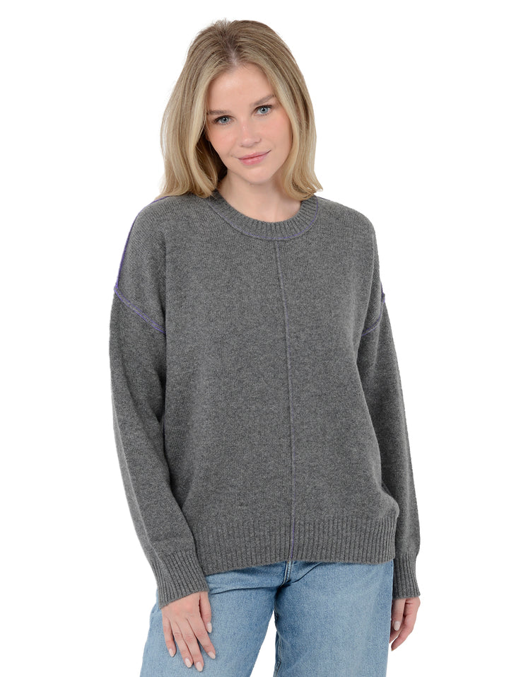 Front facing shot of model wearing Venise in gravel grey. The sweater is oversized and made of cashmere and recycled cashmere. The sweater is a crewneck pullover with decorative reversed seams.