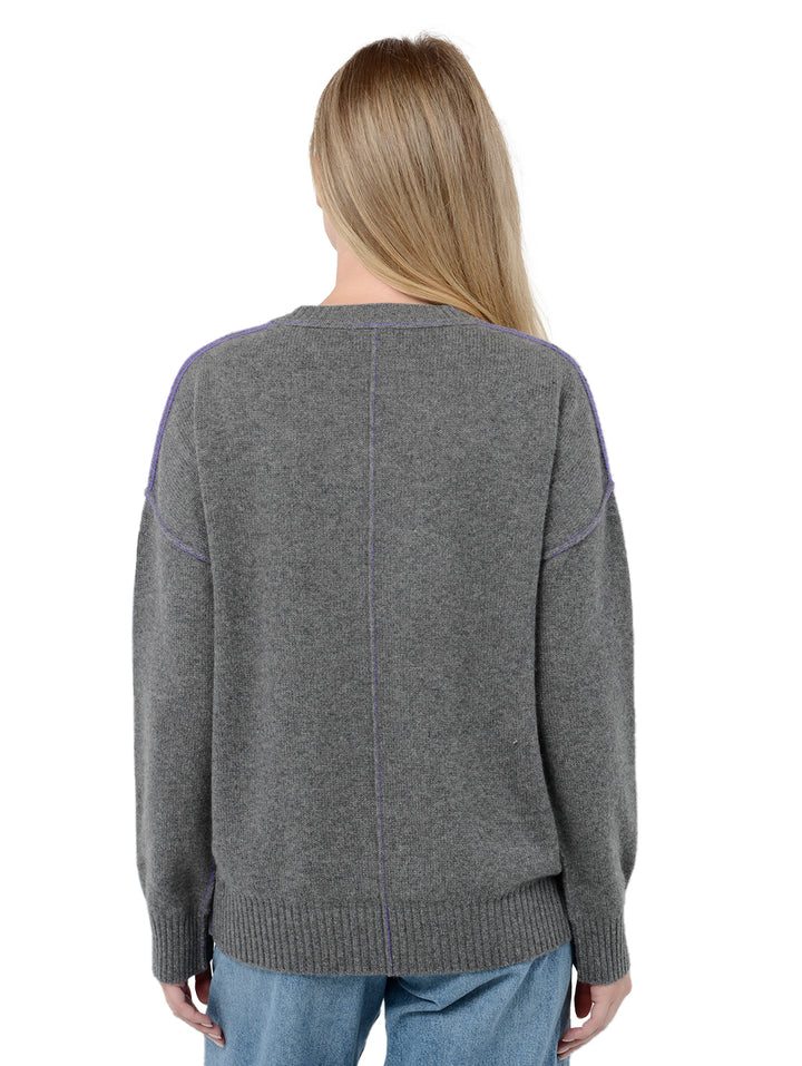 Back facing shot of model wearing Venise in gravel grey. The sweater is oversized and made of cashmere and recycled cashmere. The sweater is a crewneck pullover with decorative reversed seams.