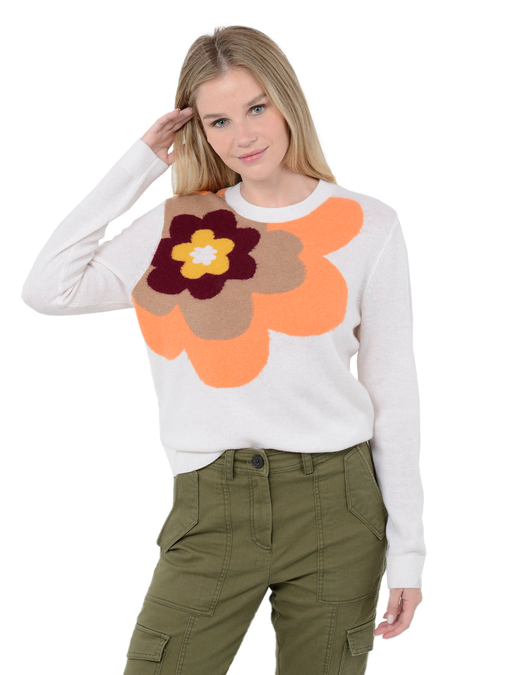Front facing shot of model wearing Alston in chalk white. The sweater is straight fit and made of cashmere, wool, and silk. The sweater is a crewneck pullover and has a large retro flower intarsia artwork.