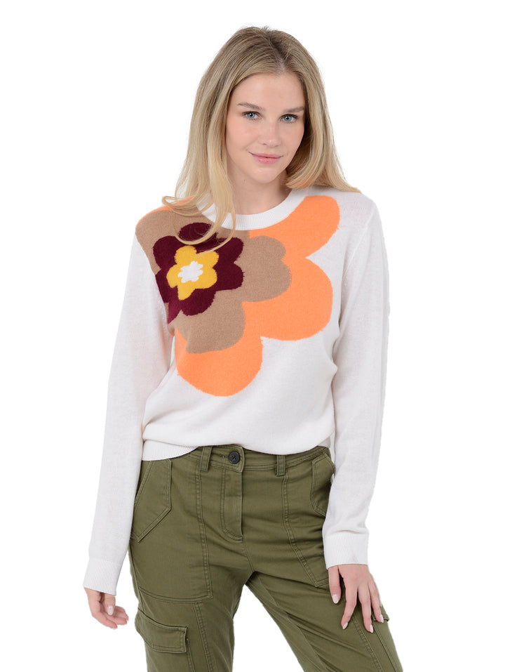 3/4 front facing shot of model wearing Alston in chalk white. The sweater is straight fit and made of cashmere, wool, and silk. The sweater is a crewneck pullover and has a large retro flower intarsia artwork.