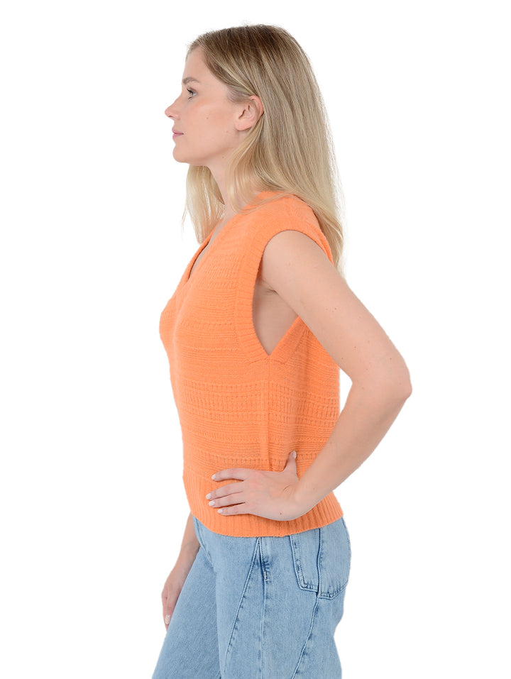 Side view of model wearing Amari in apricot orange. The sweater is straight and cropped and made of cashmere and silk. The vest has a subtle textured knit and v-neck.