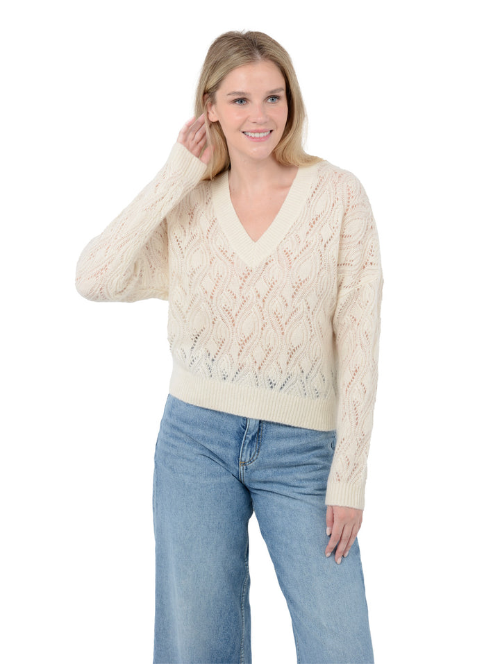 Front facing shot of model wearing Mckinnon in cloud white. The sweater is relaxed and made of cashmere and silk. The sweater also sports a v-neck, drop shoulder, and organic pointelle knit.