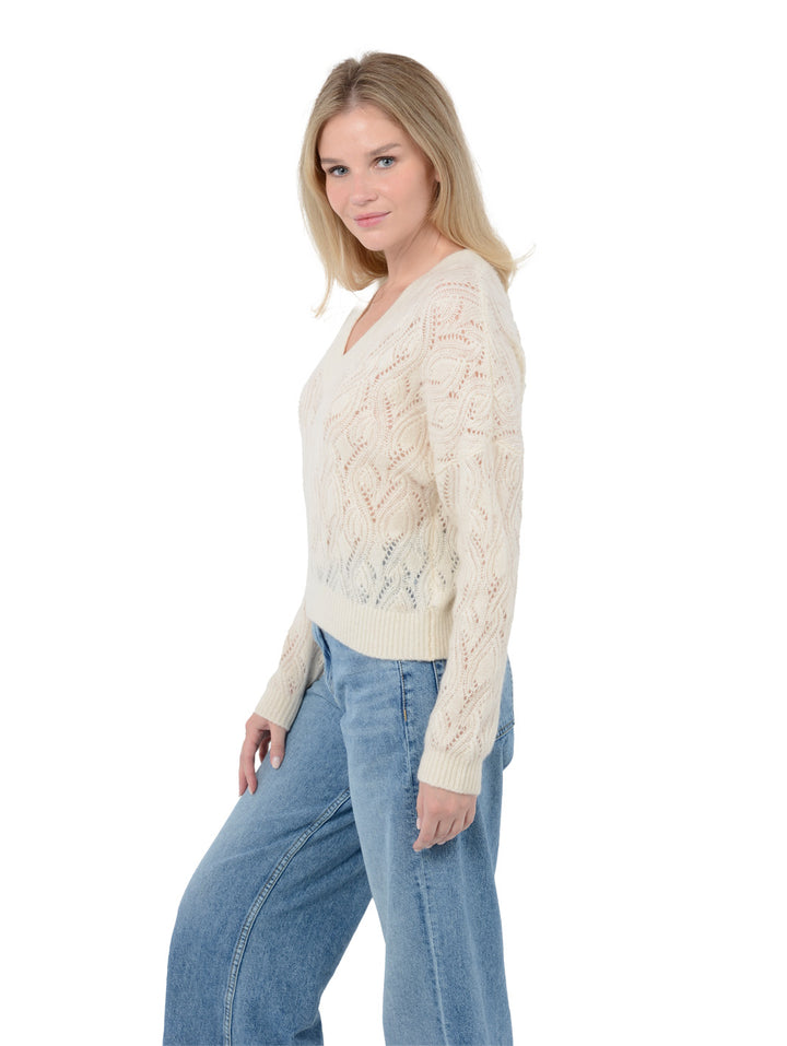 Side view shot of model wearing Mckinnon in cloud white. The sweater is relaxed and made of cashmere and silk. The sweater also sports a v-neck, drop shoulder, and organic pointelle knit.