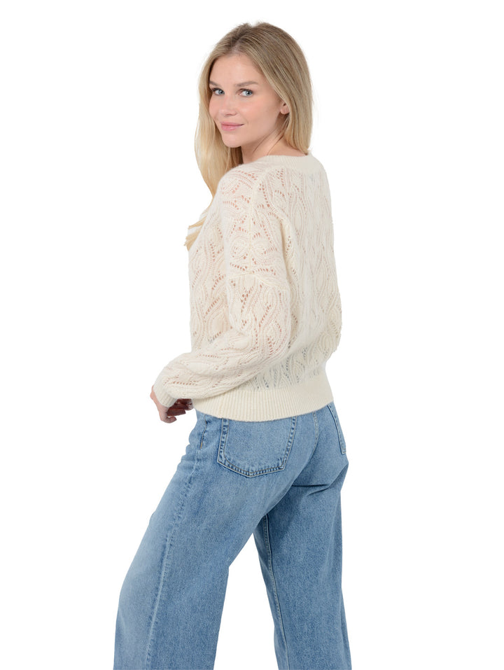 3/4 back view of model wearing Mckinnon in cloud white. The sweater is relaxed and made of cashmere and silk. The sweater also sports a v-neck, drop shoulder, and organic pointelle knit.