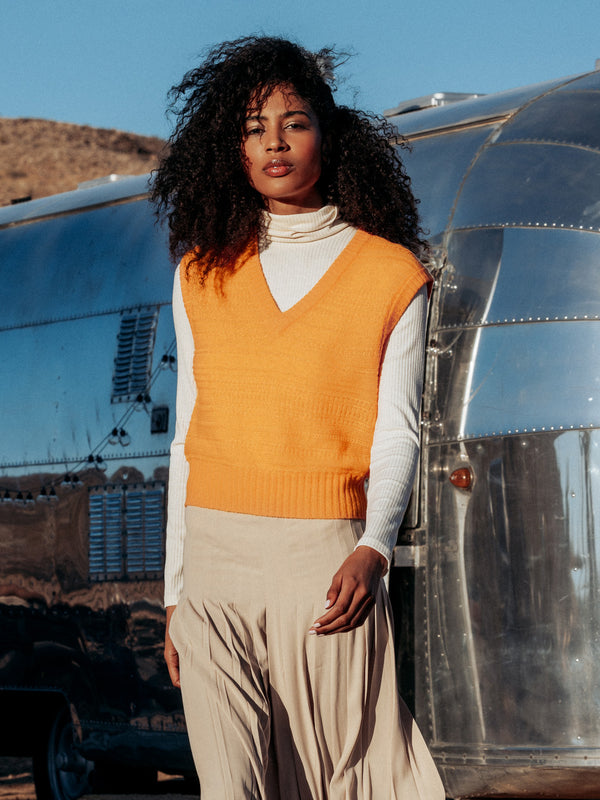 Editorial shot of model wearing Amari in front of a camping trailer in the desert. Sweater is straight and cropped and made of cashmere and filament silk.