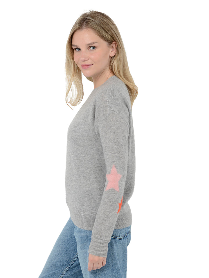 Side view of model wearing Rowan in heather gray. The sweater is straight fit and made of cashmere and silk. The pullover has colorful stars on the back of the arm.