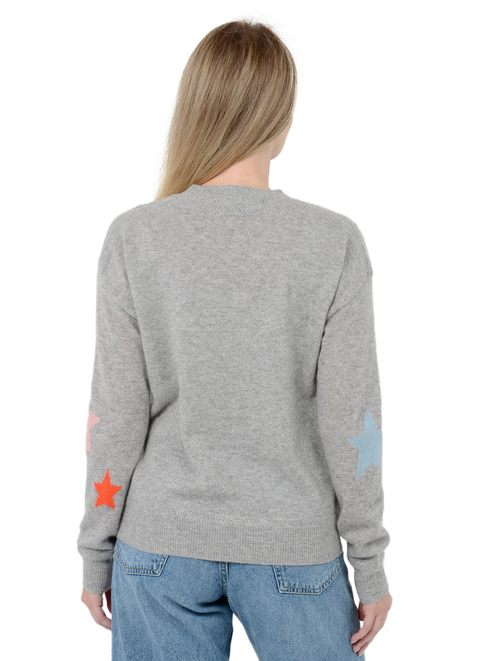 Back facing shot of model wearing Rowan in heather gray. The sweater is straight fit and made of cashmere and silk. The pullover has colorful stars on the back of the arm.