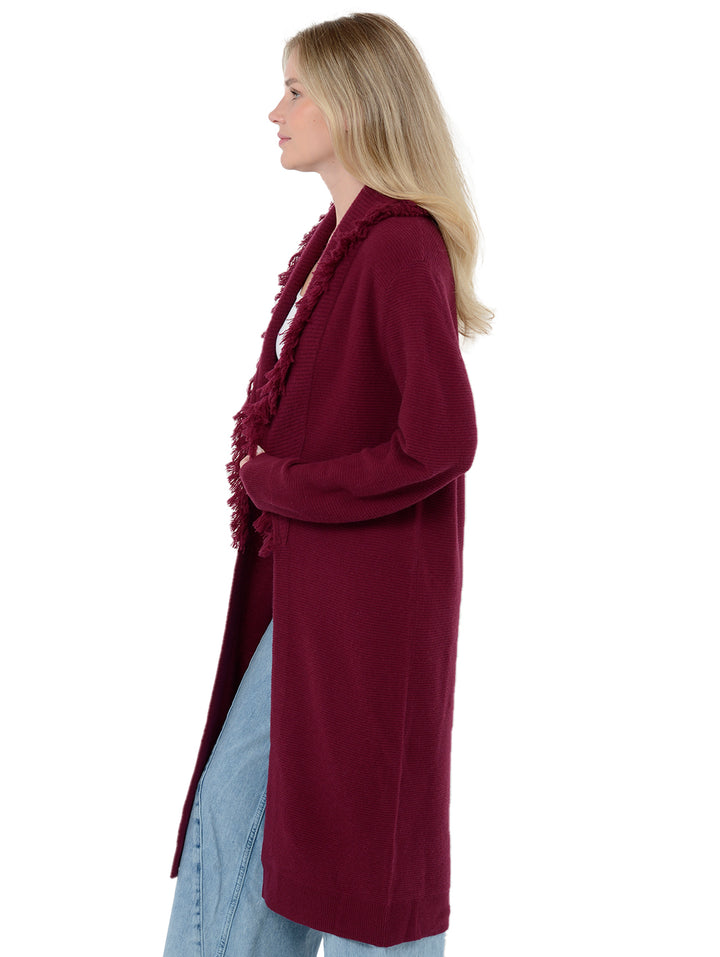 Side view of model wearing Murray in pinot burgundy. The sweater is relaxed and made of wool and cashmere. The cardigan is past knee-length and features fringe on the lapel.