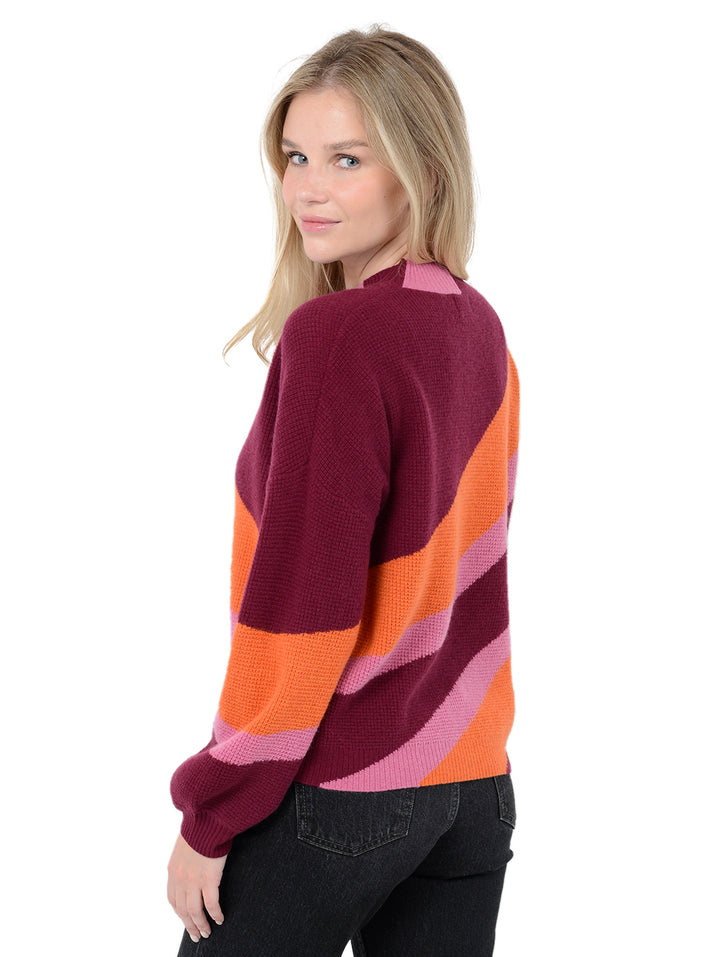 3/4 back facing shot of model wearing Norton in pinot burgundy. The sweater is oversized and made of 70% wool and 30% cashmere. The sweater is a mockneck and features diagonal stripes.