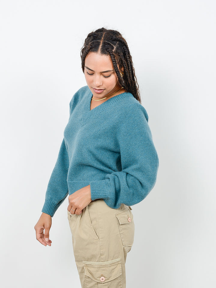 3/4 view of model wearing Binney in fern green. The sweater is straight fit and made of cashmere and recycled cashmere.