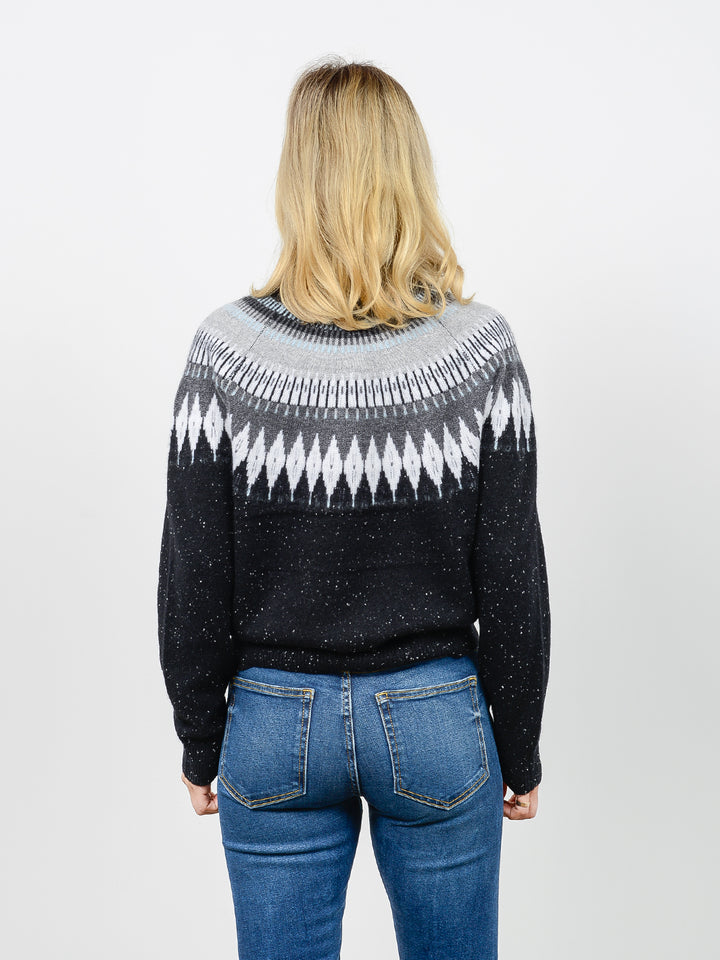 Back facing shot of model wearing Salena in tinder black. The sweater is relaxed and made of 100% cashmere. The sweater also sports a fairisle knit design across the chest and neck.