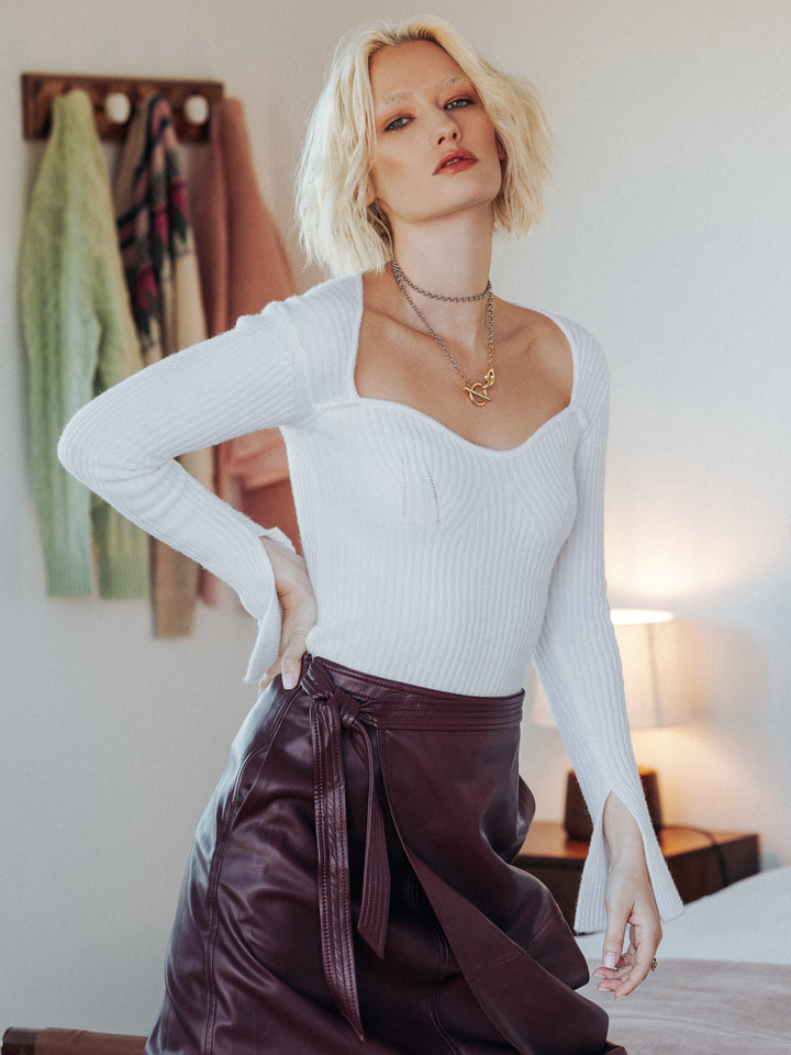 Editorial shot of model wearing sweetheart-neck sweater Gwenevere. She is wearing the sweater paired with a pleather skirt.