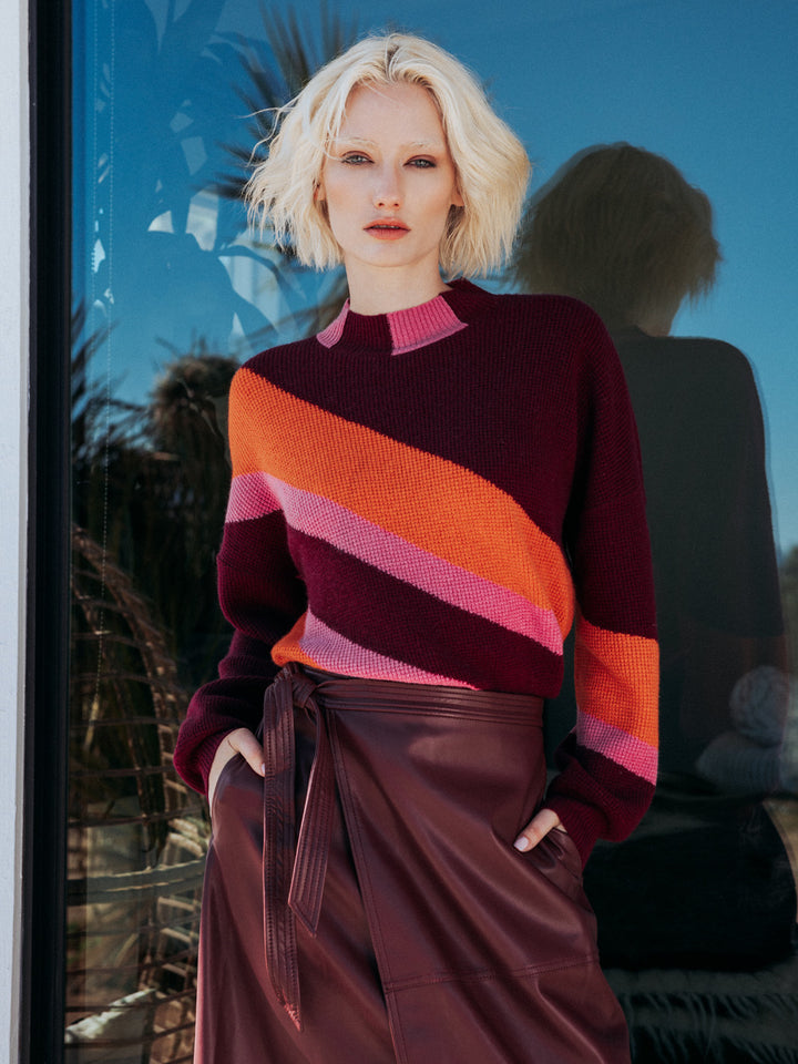 Editorial shot of model wearing norton striped sweater with her back to a reflective window.